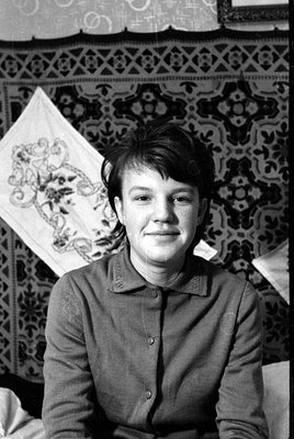A black and white portrait of a man wearing a button-up shirt, oriented sideways. He is lying on a patterned rug next to a wh...