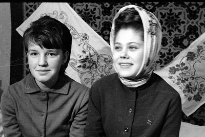 Black and white portrait of two young women. The woman on the right wears a light-colored patterned headscarf, while the woma...