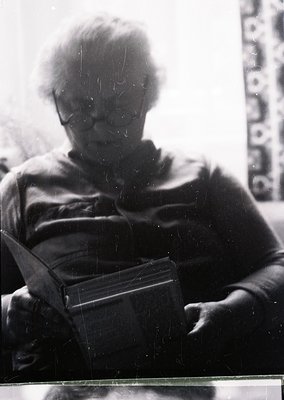 Vintage black-and-white portrait of an individual holding a vintage camera, likely a Leica-style rangefinder. The person’s sh...