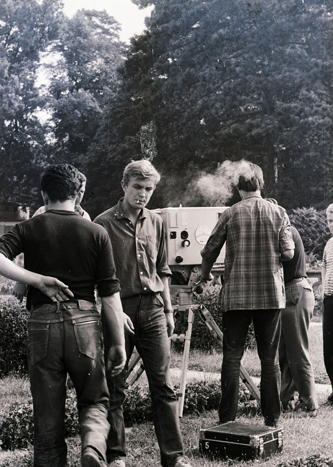 Crew with a tripod-mounted camera among the trees