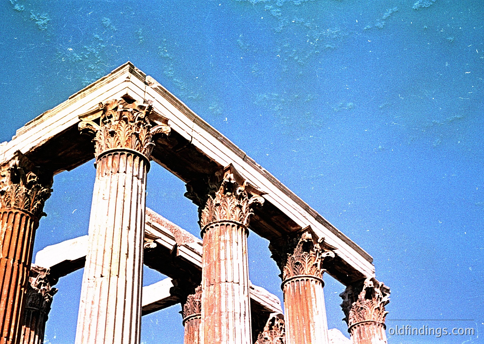 Ancient Corinthian columns under clear blue sky, showcasing intricate acanthus leaf capitals. Likely part of a Roman or Greek ruin, possibly in () or (). --- *Note: Exact location indeterminable without metadata, but style aligns with Hellenistic/Roman ruins.*