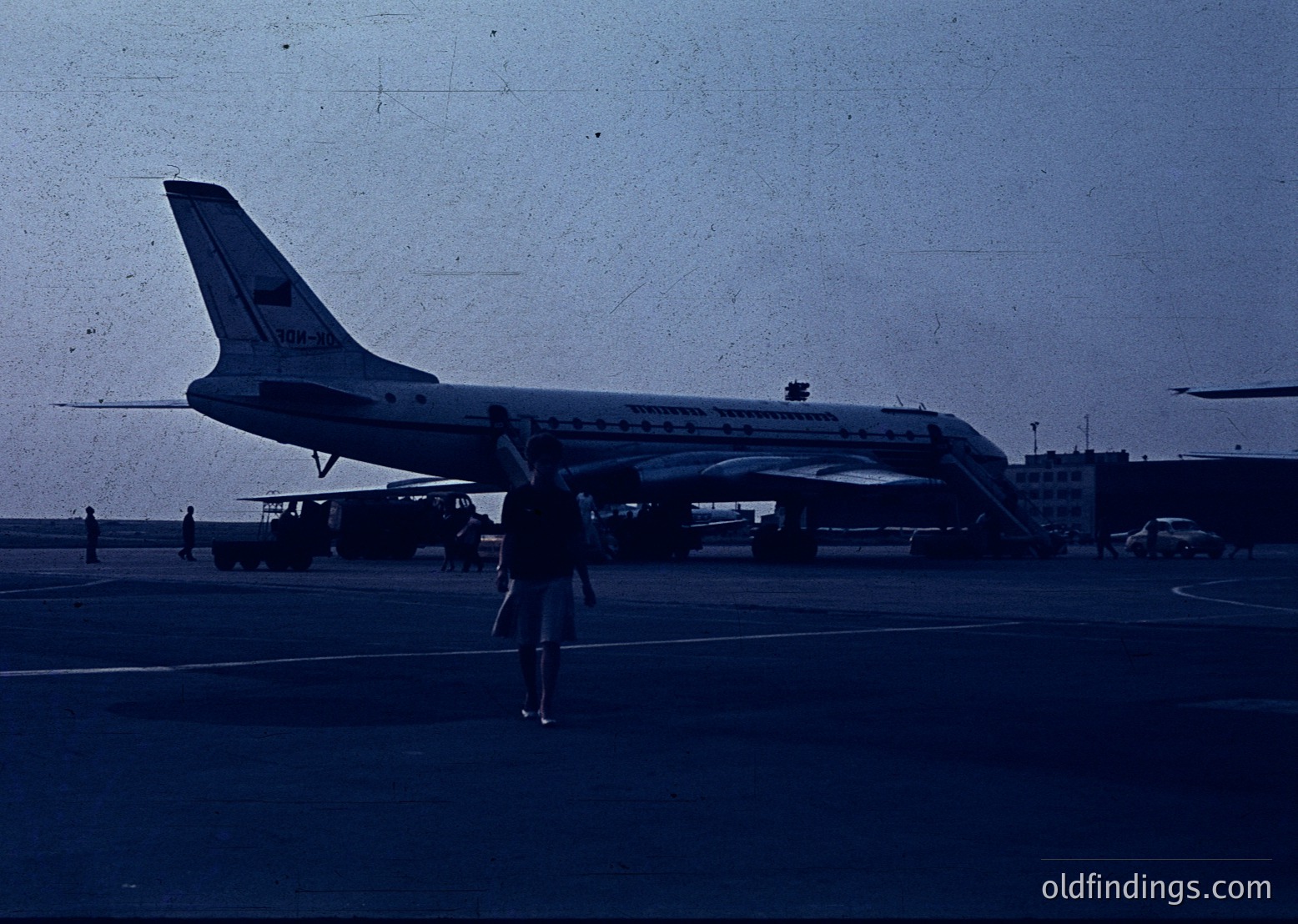 Vintage Soviet Aeroflot Tupolev Tu-134 jetliner parked at an airport tarmac, marked with Cyrillic "Аэрофлот" and "ТУ-134" on tail. Passenger in shorts walks toward aircraft, mid-20th century Soviet-era aviation.