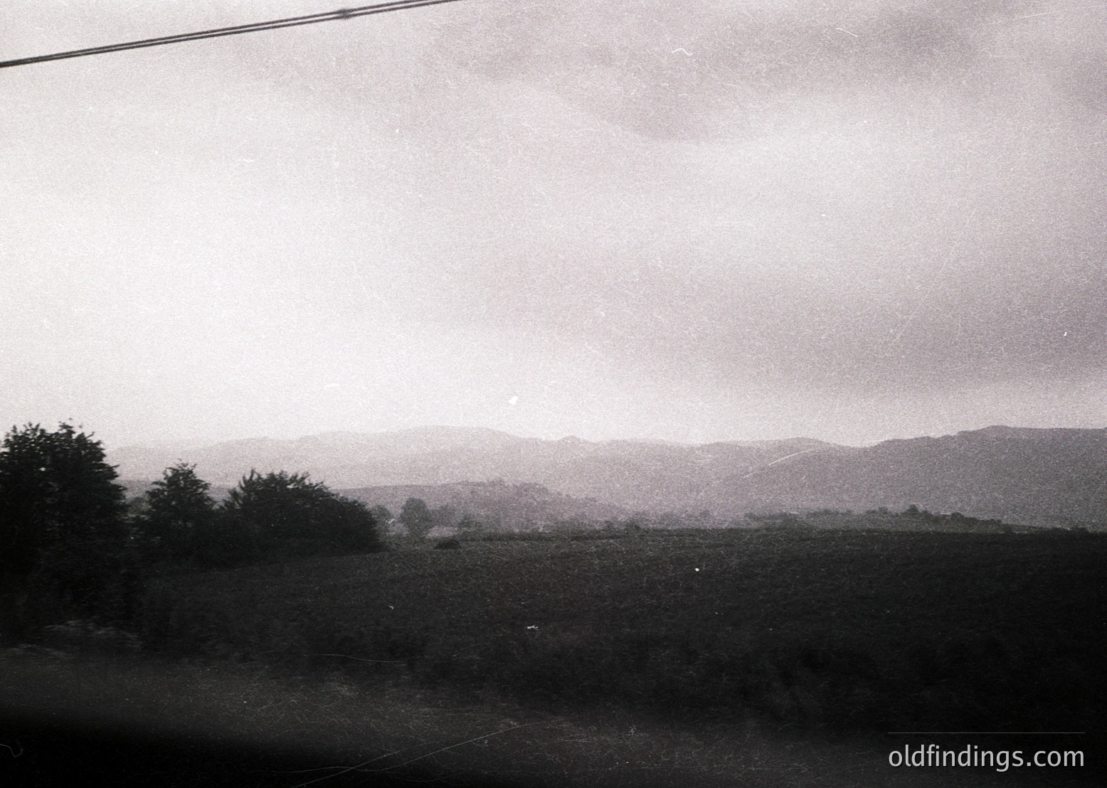Mid-20th century black-and-white landscape shot of rolling hills and sparse vegetation under overcast skies. Low-contrast, grainy texture suggests vintage film. Possible rural European countryside, likely 1950s–1970s.