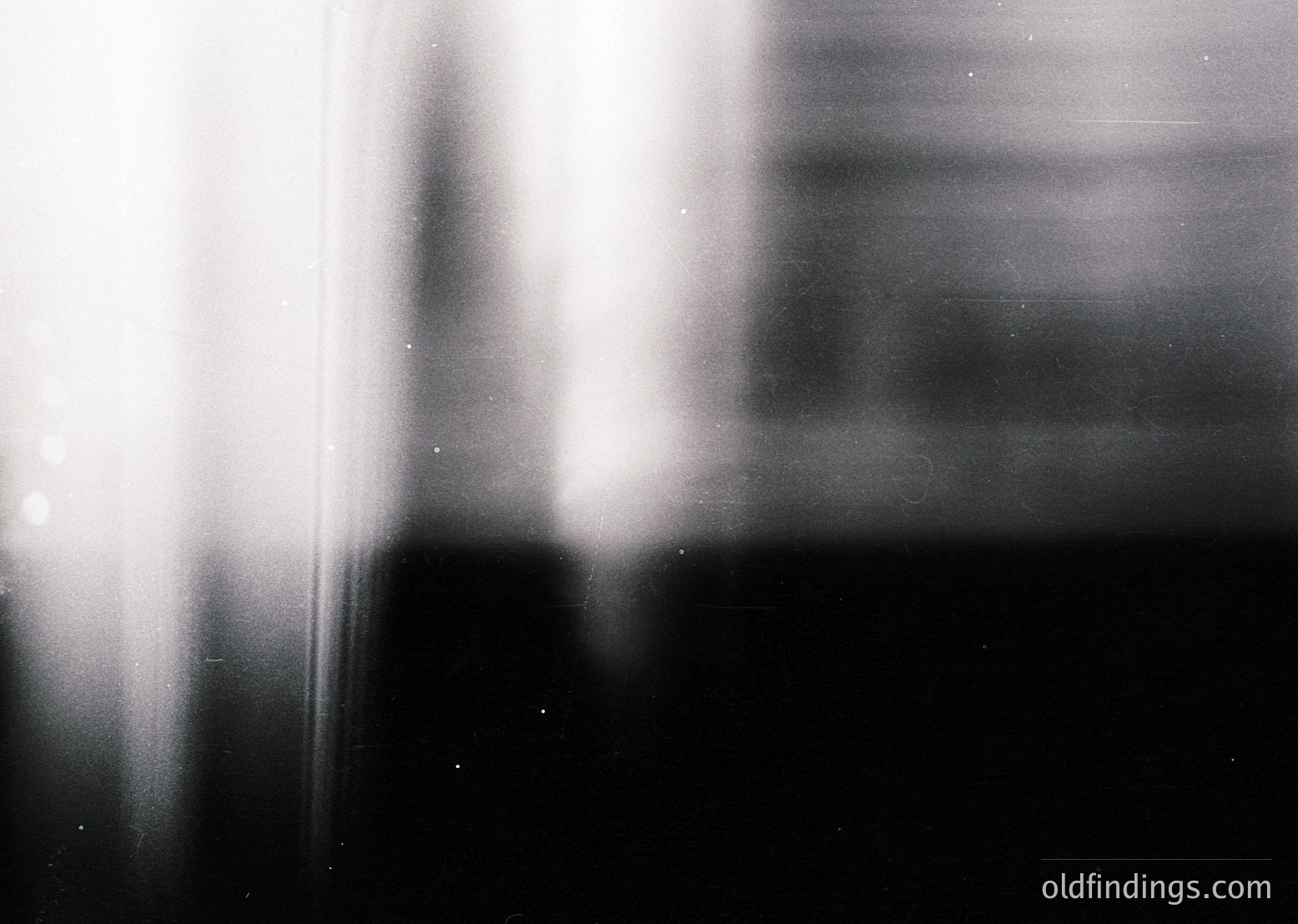 High-contrast black-and-white abstract of blurred vertical lines and light streaks, likely from motion or long exposure. Evokes urban or industrial setting with dynamic energy. Potential for artistic or experimental photography references.