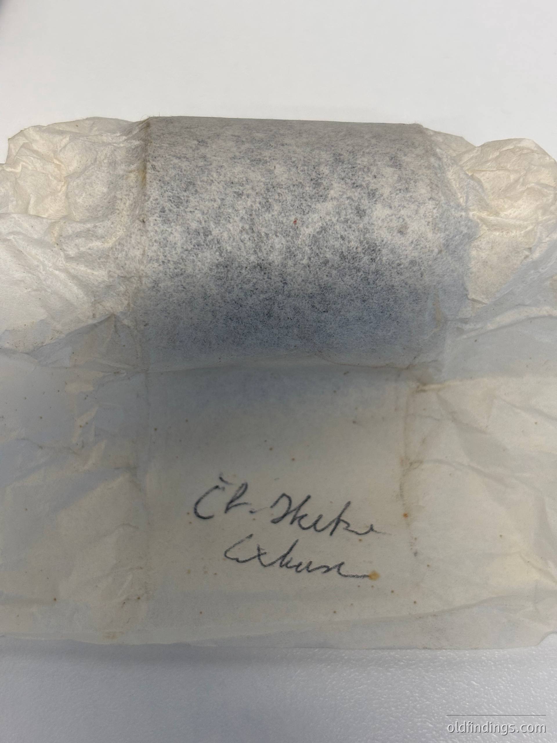 Vintage paper wrapping with handwritten Cyrillic inscription "Ел. Дике" and "Експо" on a rectangular stone block, likely a decorative or architectural fragment. The paper shows signs of aging and wear, suggesting historical or archival significance. Potential connection to Bulgarian cultural heritage or Soviet-era construction materials.