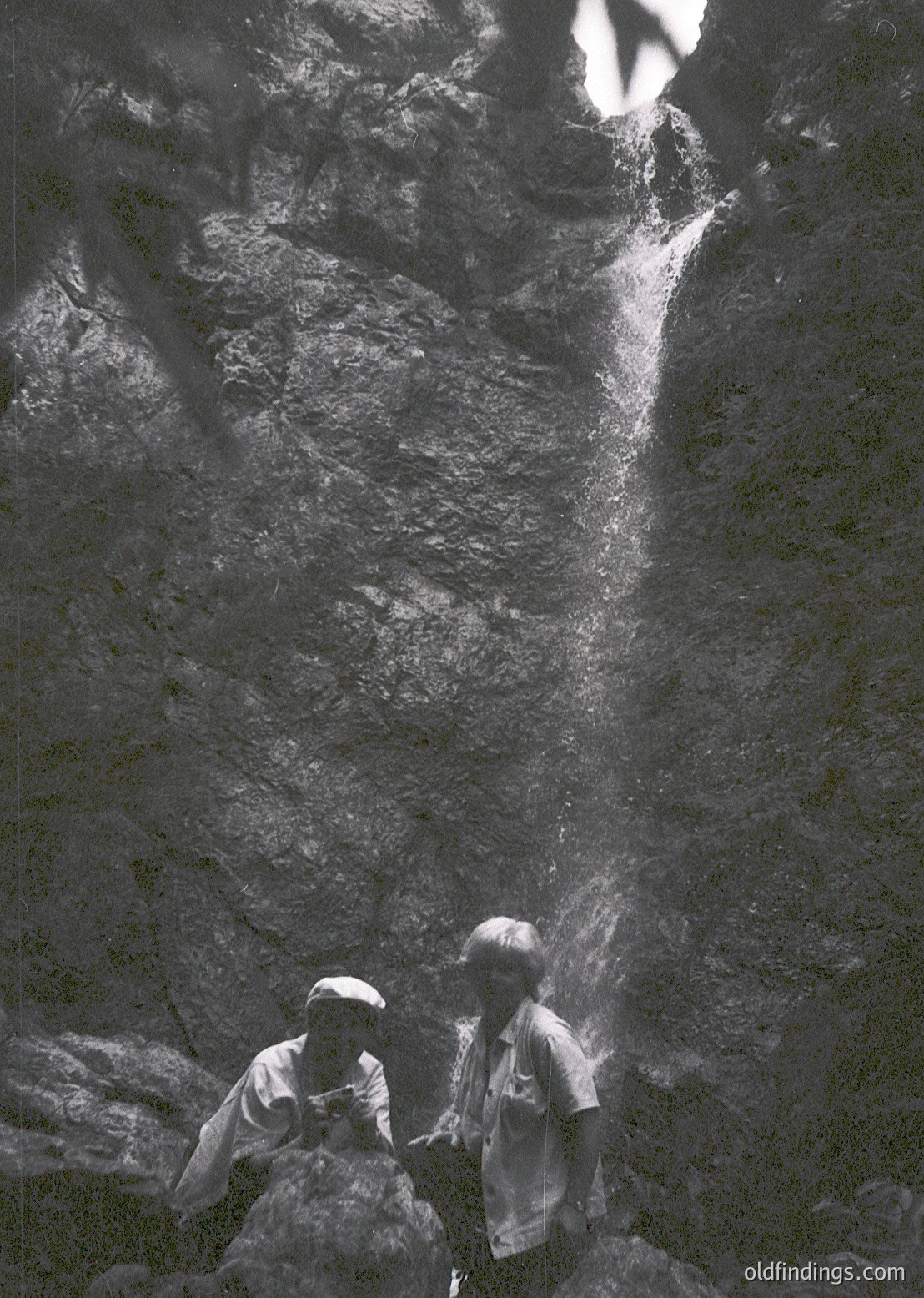 Two children stand beneath a powerful waterfall, their faces partially obscured by mist. Mid-century outdoor photography captures their youthful curiosity amid nature’s raw force. Likely –, , , , .