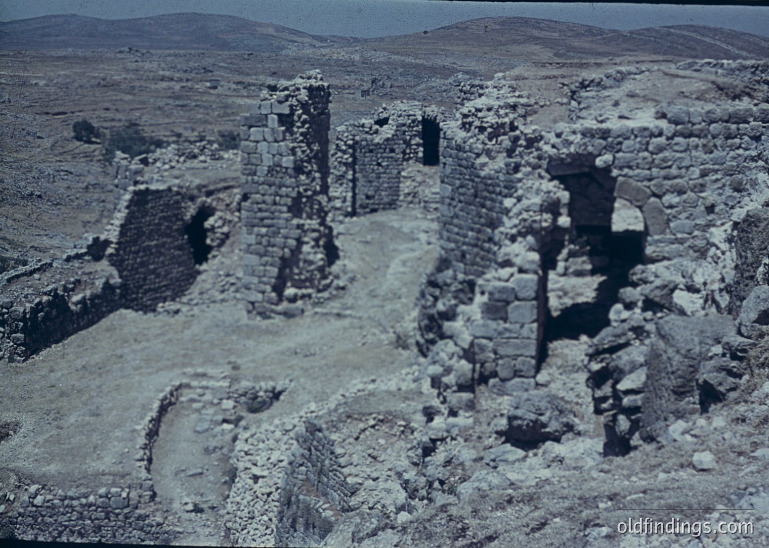 Ancient stone ruins in arid landscape, featuring partial walls and doorways. Likely Byzantine or early medieval fortress remains, indicative of defensive architecture. Dry, rocky terrain suggests Mediterranean or Near Eastern region.