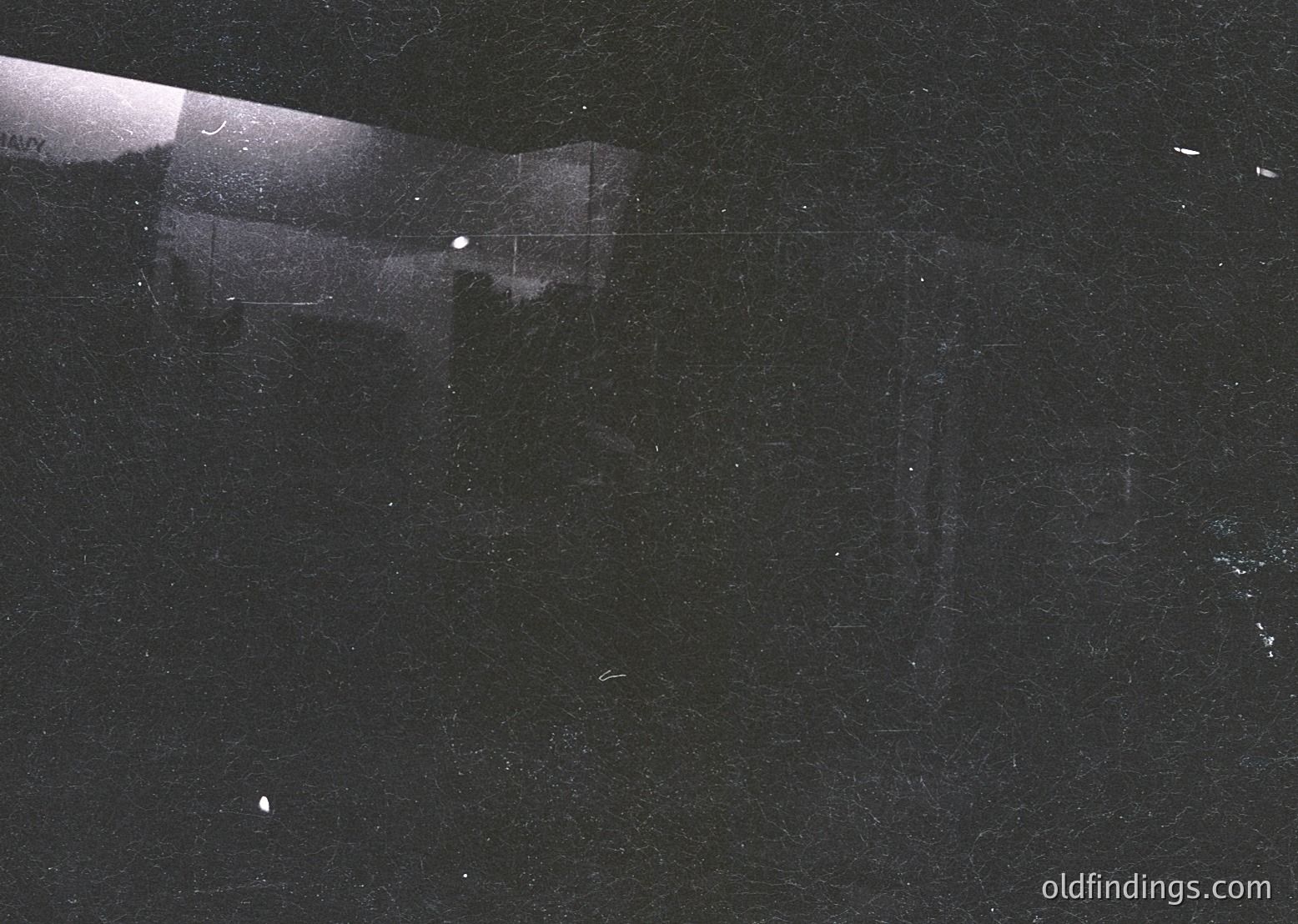 High-contrast black-and-white shot of a **mid-century modernist building corner** at night, illuminated by a single vertical light source. Clean lines, geometric angles, and minimalist design suggest **1950s–1970s architectural experimentation**. Potential urban or institutional use.