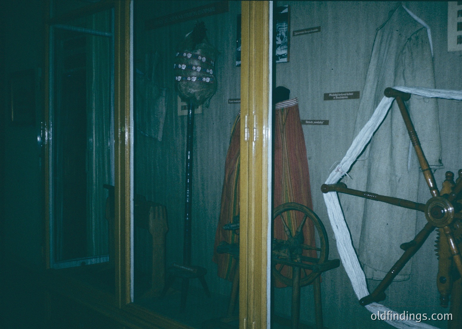 Vintage maritime display featuring a wooden ship’s wheel, rope-laden pulley system, and a traditional striped sailor’s jacket. Dimly lit interior suggests a museum or historical exhibit, likely from the 20th century.