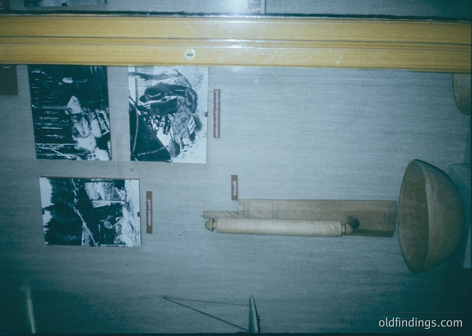 Vintage wooden megaphone mounted on a wall with three black-and-white aerial photographs in frames. Likely from mid-20th century industrial or military archives.