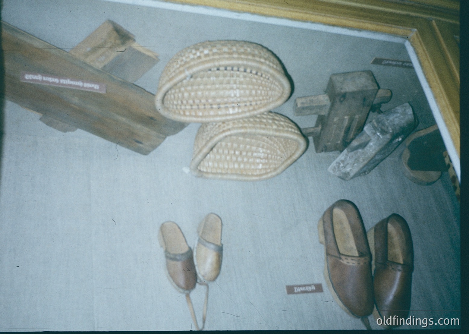 Handcrafted footwear display featuring traditional leather sandals with woven straw soles, wooden clogs, and embroidered slippers. Likely from a folk craft or ethnographic exhibit.