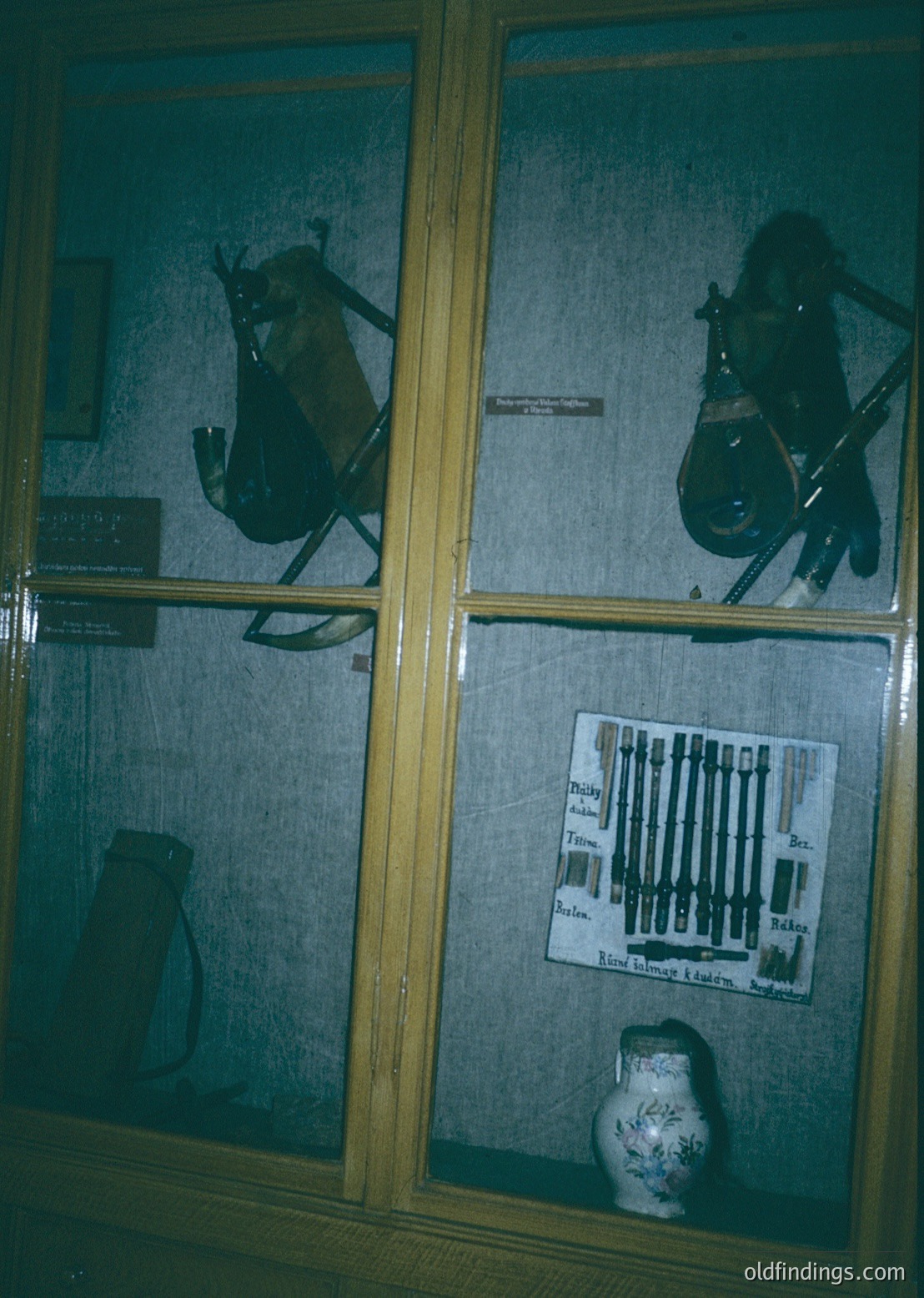 Display case showcasing mounted animal heads (likely deer) and historical weaponry (rifles, bayonets) alongside vintage pottery. Labels indicate items from the 19th–early 20th century. Ideal for historical research or museum exhibits.