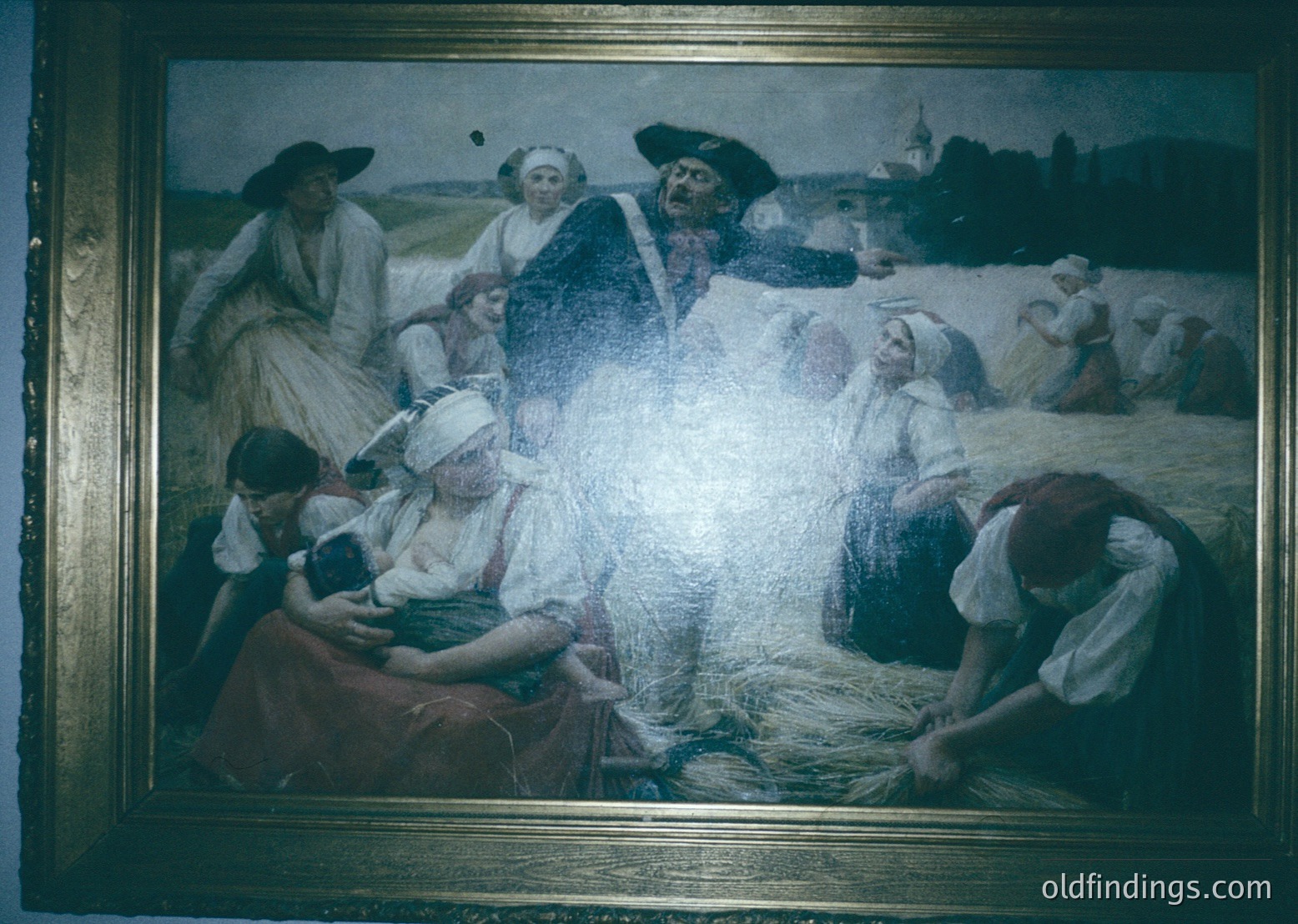 Vintage painting depicting rural harvest scene with 10+ figures in period attire (19th-century European). Central figure in elaborate costume likely represents folklore or religious tradition. Women bind sheaves, children assist, under hazy sky. Golden frame enhances aged aesthetic.