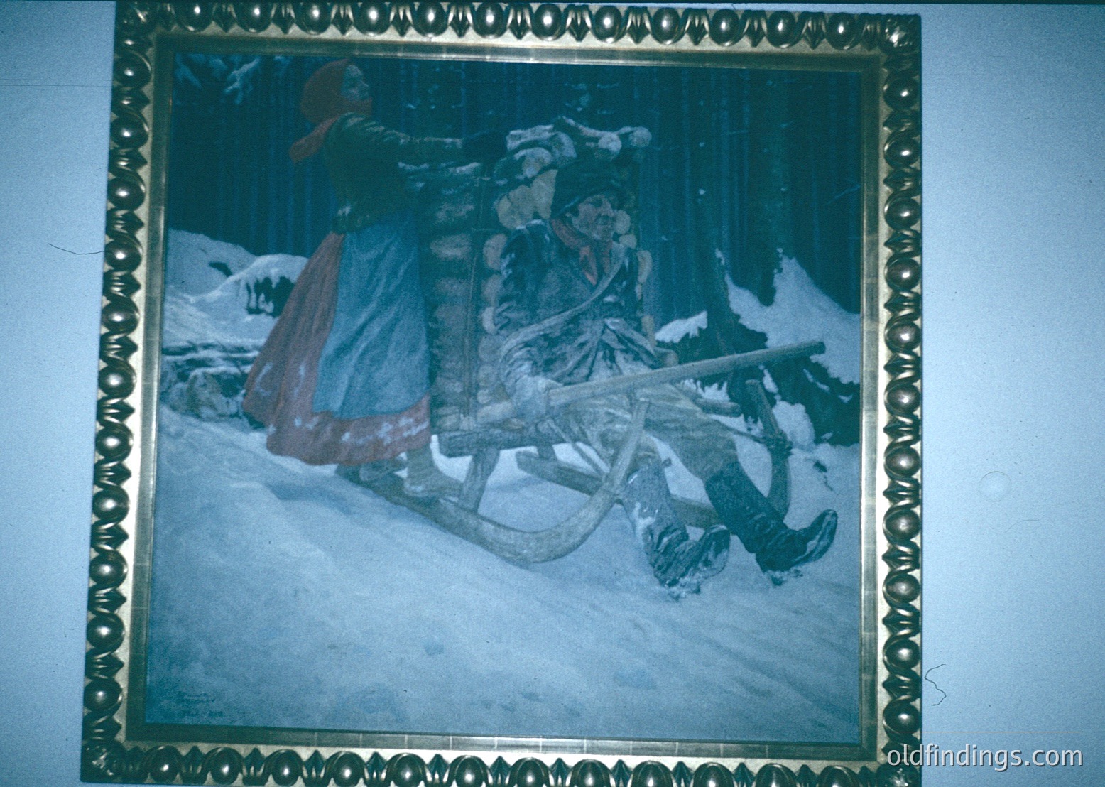 Vintage sepia-toned illustration of two figures sledding in a forested winter landscape, framed in ornate gold. Likely 19th–early 20th century European folk art.