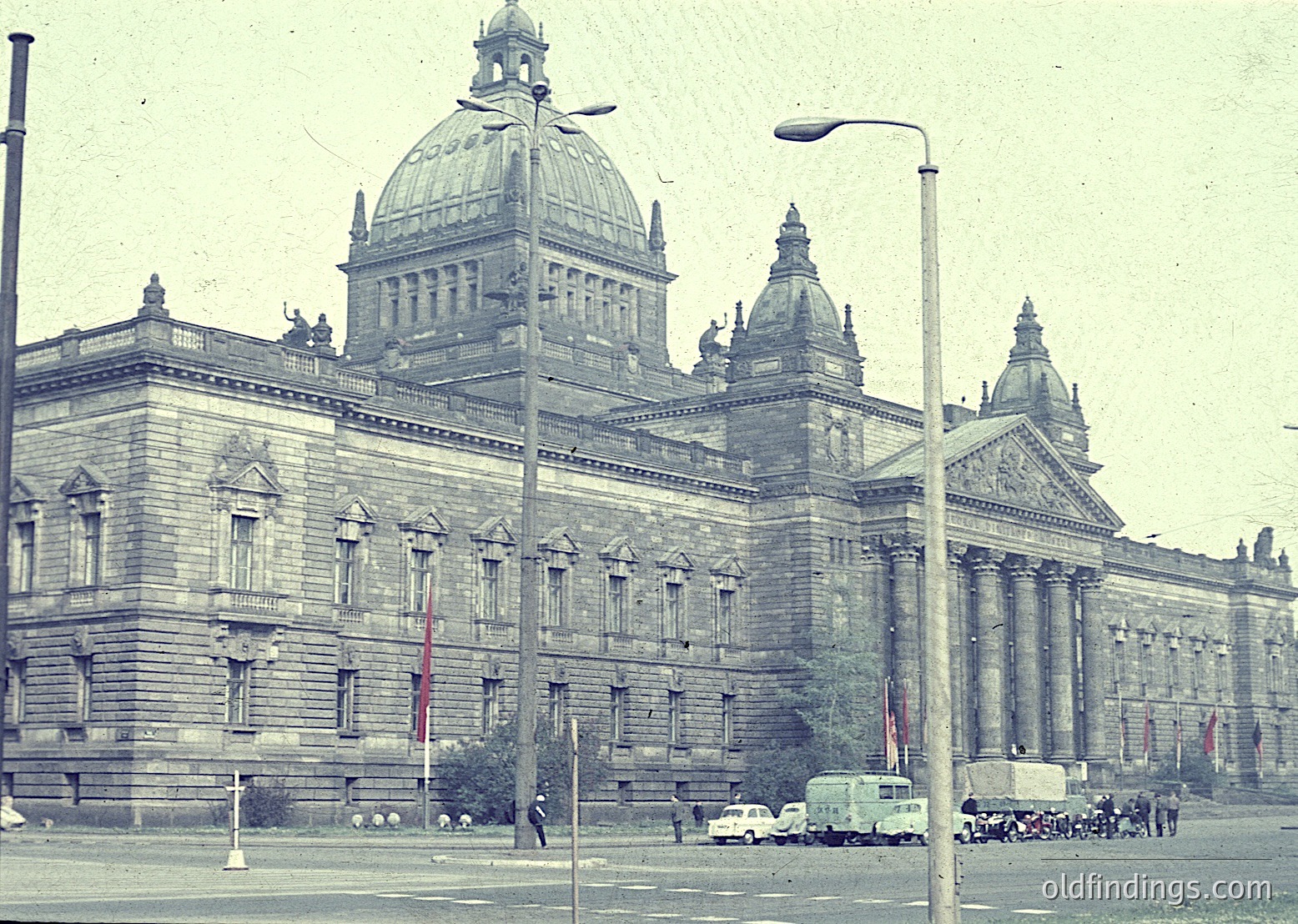 Neoclassical building with domed central tower and symmetrical façade, featuring columns and ornate stonework. Likely a government or cultural institution from the early-to-mid 20th century. Urban street scene with vintage vehicles and pedestrians.