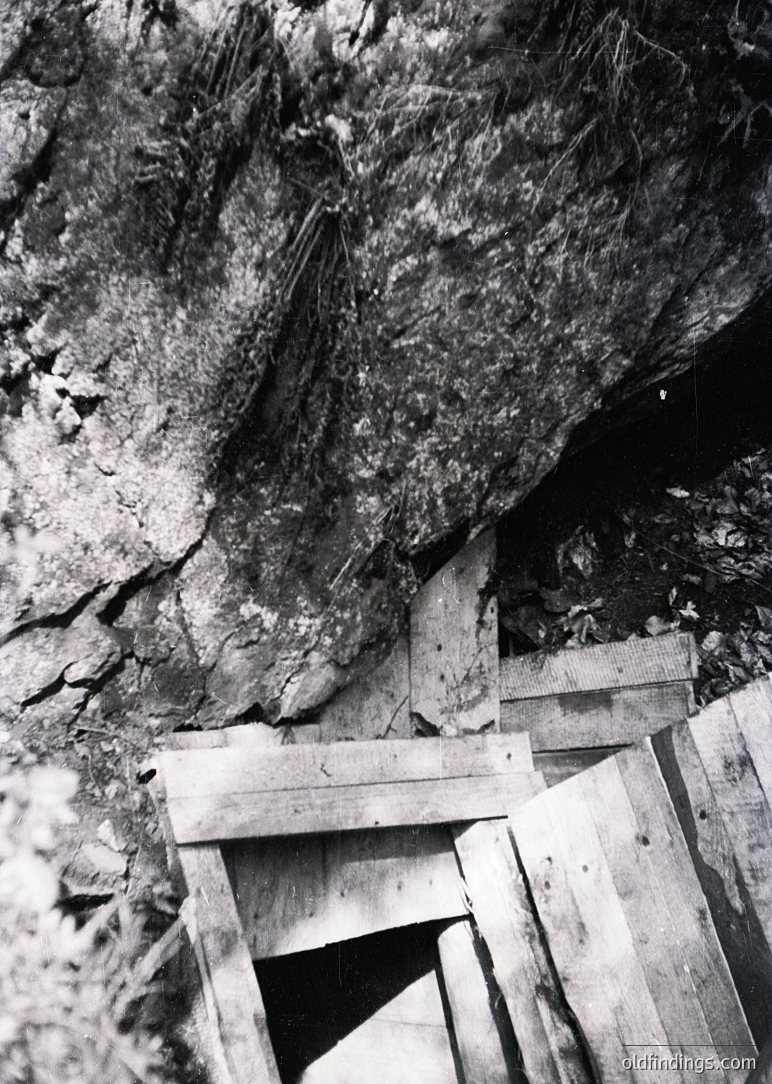 Industrial-era wooden support beams and rock face in a mine shaft, likely coal or ore extraction. Rustic timber framing stabilizes unstable rock layers. Mid-20th century mining infrastructure.