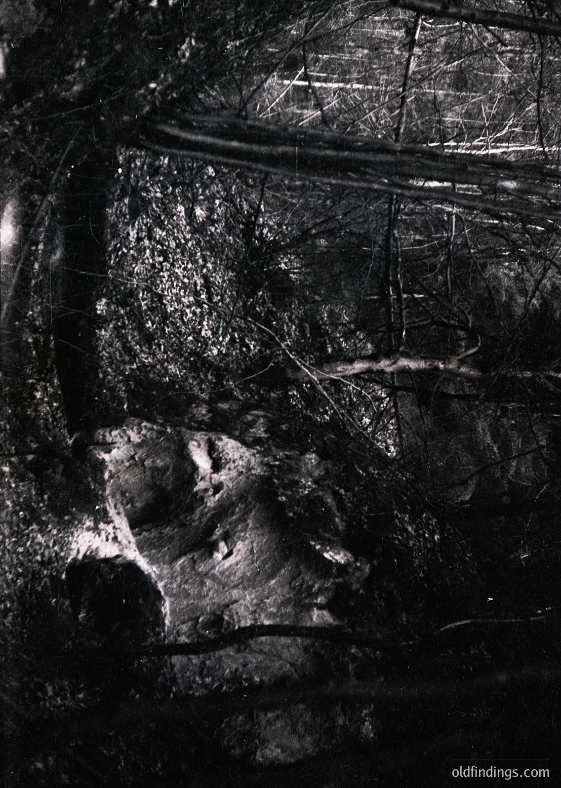 High-contrast black-and-white close-up of a weathered, textured stone surface with intricate carvings resembling a reclining figure. Likely part of an ancient or medieval architectural relief, possibly a tomb or monument. The granular detail suggests aged marble or limestone.