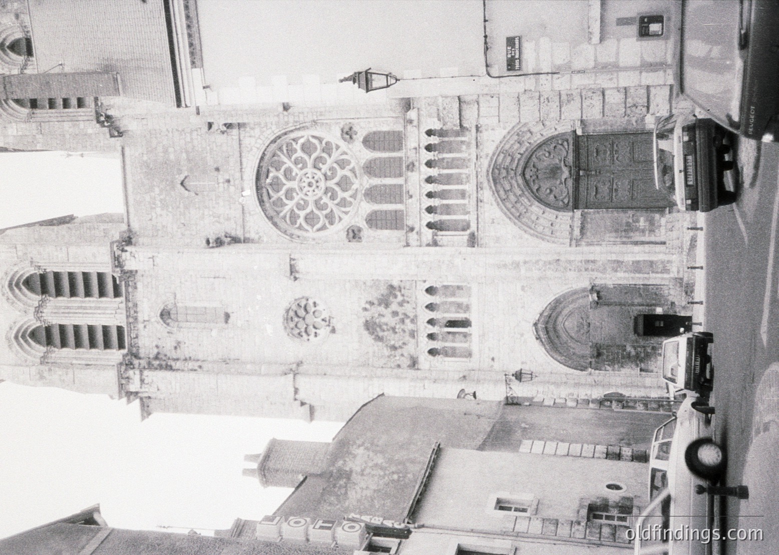 Aerial view of Gothic-style cathedral façade with rose window and pointed arches, likely 12th–16th century European architecture. Symmetrical design features intricate stonework and vertical emphasis.