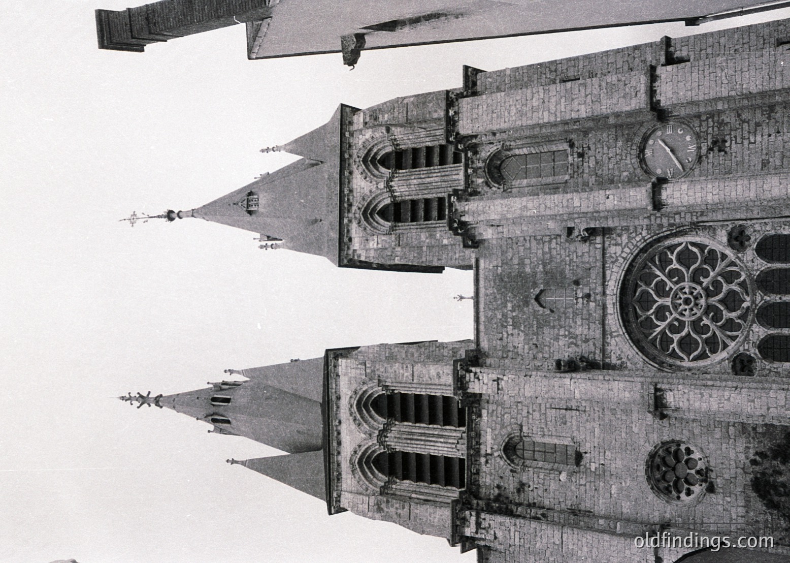 Gothic cathedral façade featuring twin spires and intricate rose window, likely 13th–16th century European architecture. Symmetrical buttresses and pointed arches highlight verticality.