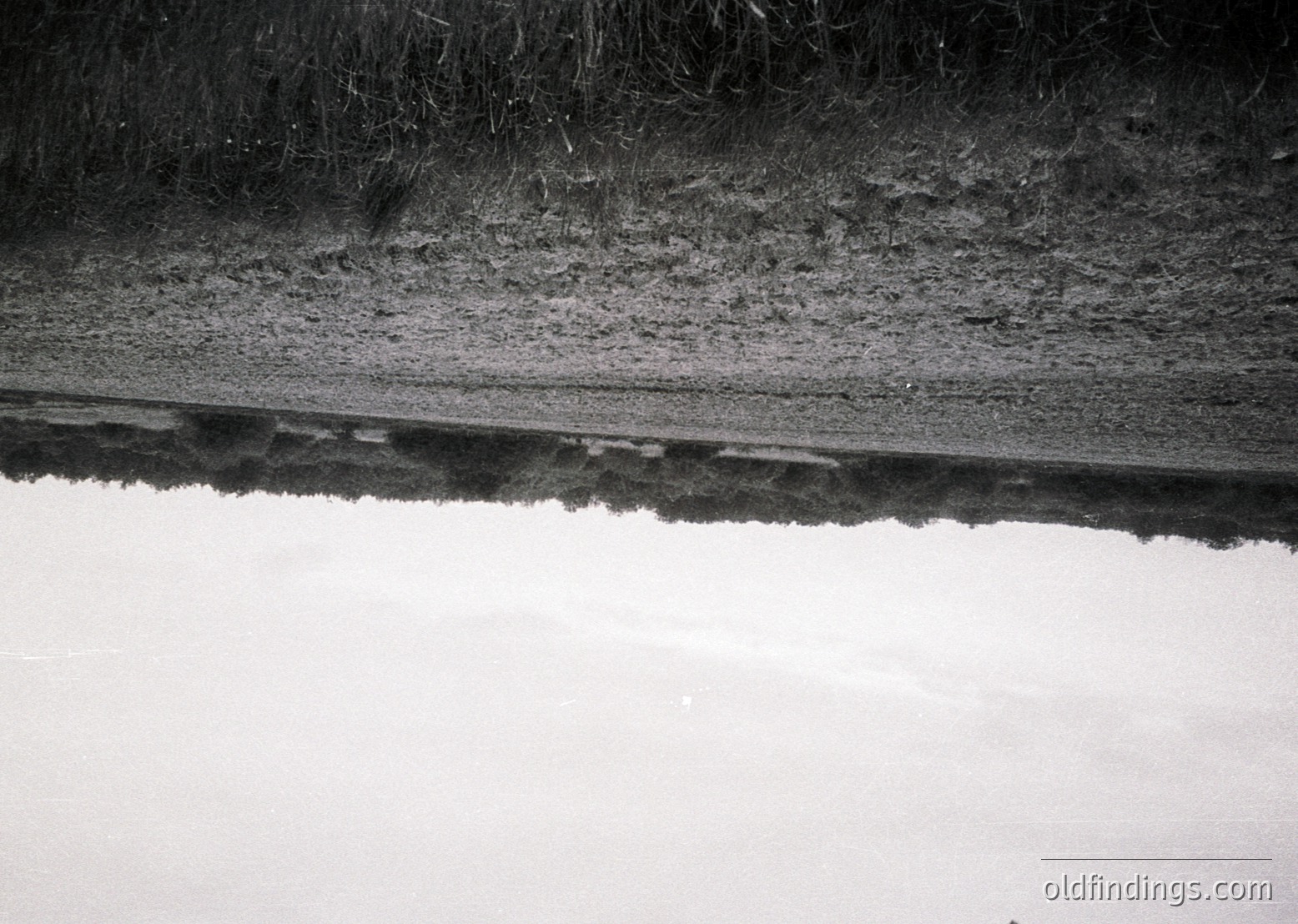 Close-up of a concrete waterfront edge with visible erosion and cracks, likely a dock or pier. The texture reveals rough concrete finish and weathered surfaces.