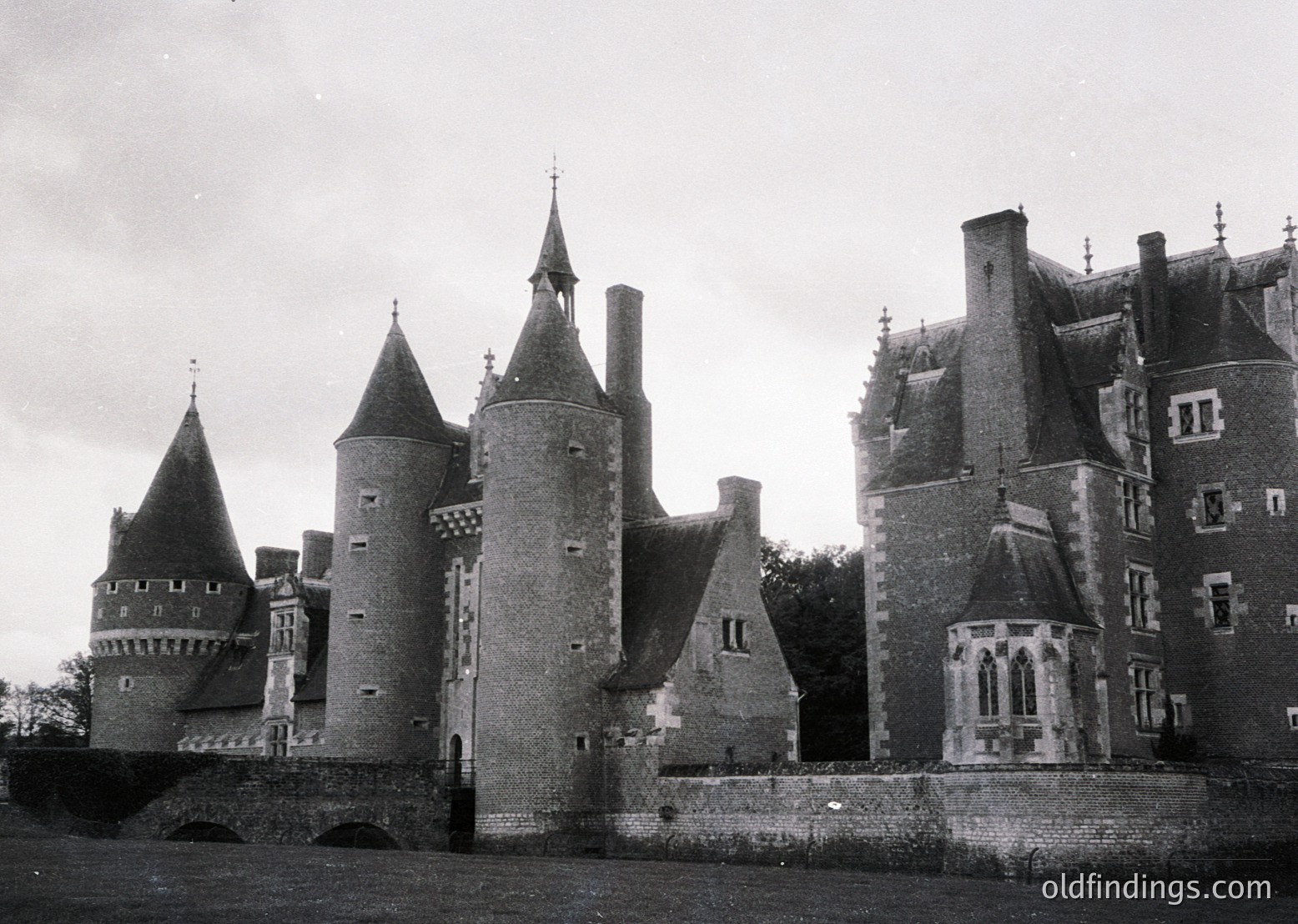 Medieval-style castle with conical towers, crenellated parapets, and arched gatehouse entrance. Architectural details include pointed turrets, small arched windows, and a central tower with decorative battlements. Likely European, possibly or early restoration.