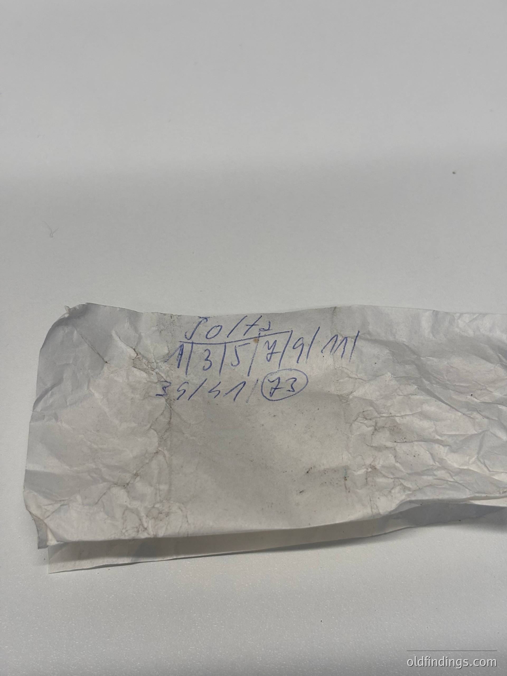 Torn aluminum foil with handwritten measurements (113.5 x 91 mm) and circled "23" in blue ink, likely for packaging or archival reference.