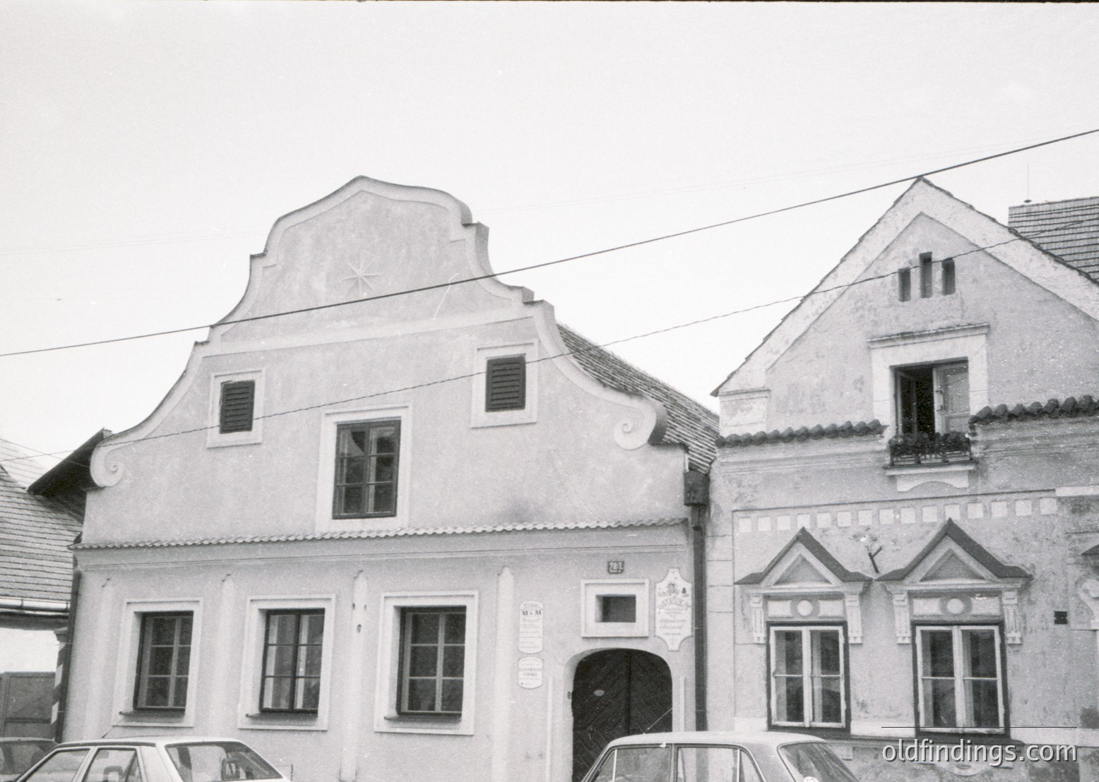 Classic Central European architectural façade featuring stepped gable roofs and decorative cornices. Symmetrical windows with wooden frames and small balconies. Likely 19th-century urban residential or commercial building.
