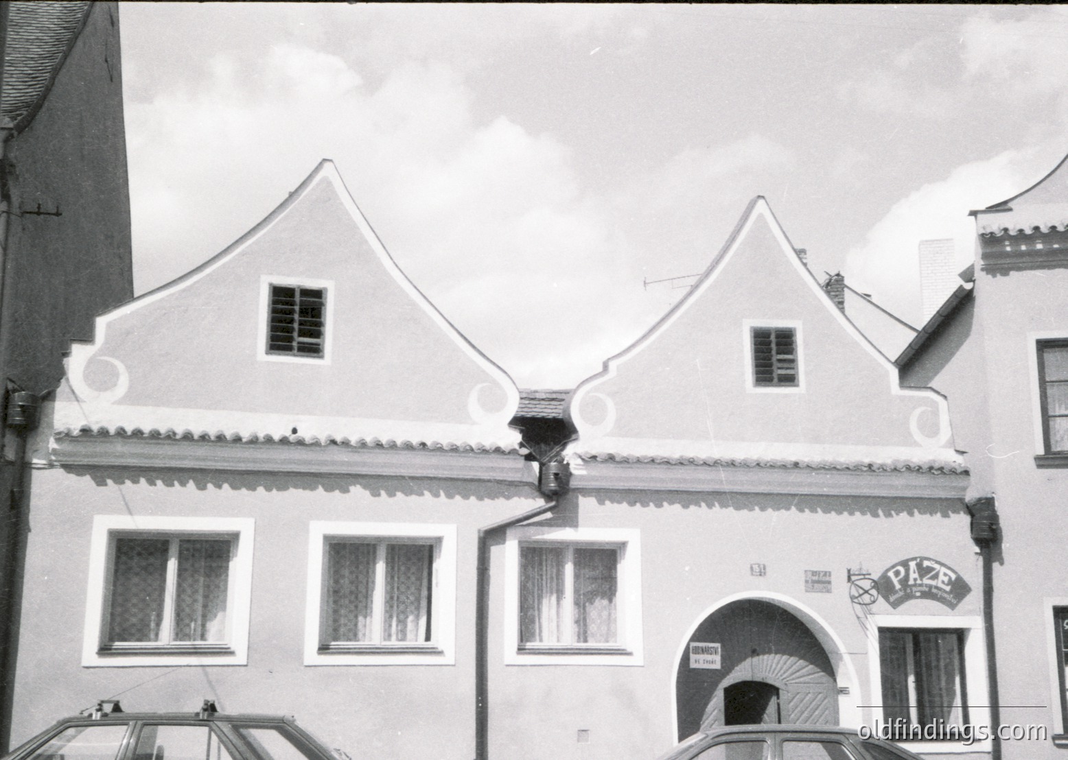 Two-story building with steep gable roofs, decorative cornice, and arched entryway. Signage reads "Pizzeria" in bold letters. Likely European alpine or Mediterranean architectural style.