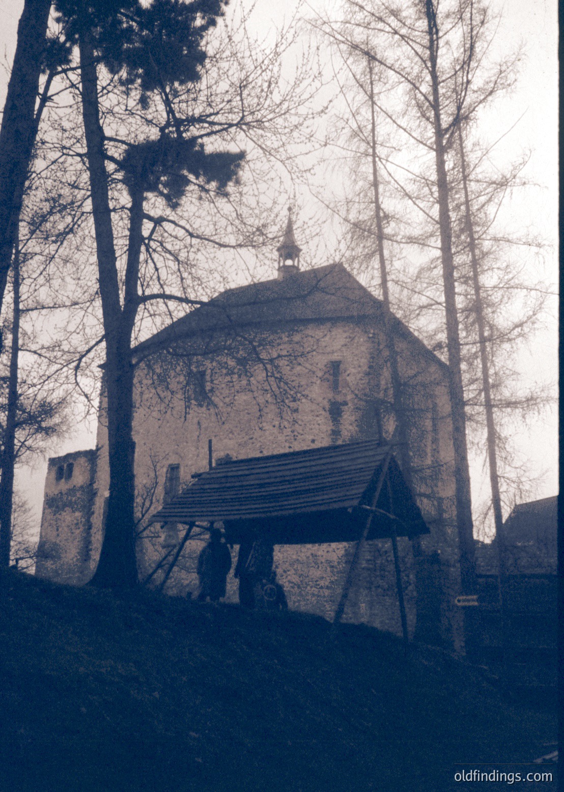 Historic stone tower with conical roof, partially covered by wooden scaffolding. Likely a medieval or early modern defensive structure in a forested European setting. *(Note: Exact location/time period indeterminate without metadata, but architectural style suggests 15th–17th century.)*