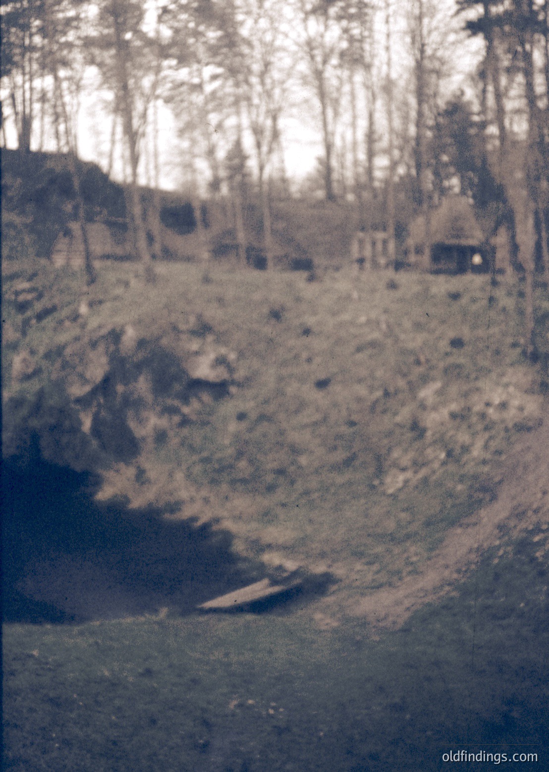 Vintage sepia-toned photo of a rugged, forested landscape with a rocky hillside and faintly visible wooden structure. Likely early 20th-century rural scene, possibly Eastern Europe.