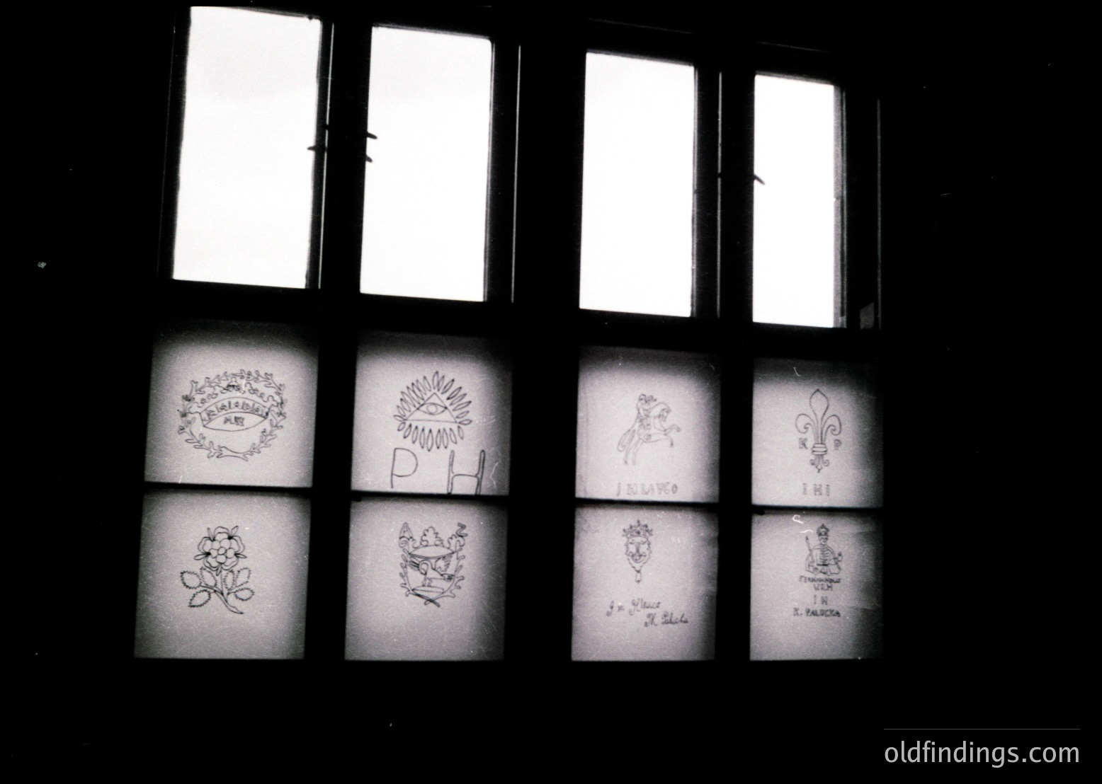 Vintage stained-glass window featuring intricate heraldic designs: fleur-de-lis, crowns, and floral motifs. Likely European, possibly or early . Ideal for historical architecture or decorative design references.