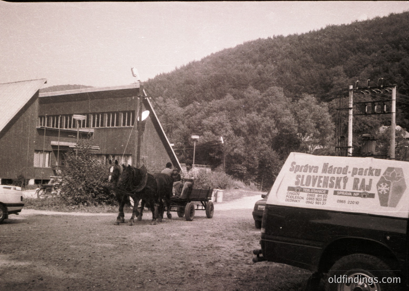 Horse-drawn cart alongside a truck labeled "Slovenský raj" (Slovak Paradise) in a rural setting, likely Slovakia. Mid-20th century industrial-style building with balconies in background.
