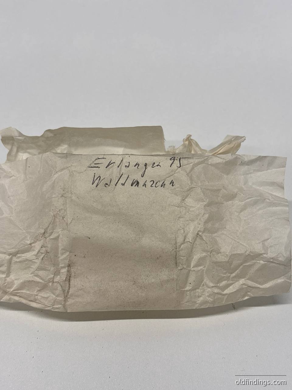 Wrinkled, aged paper envelope with handwritten text: *"Erlanger 95" / "Wollwaren"* (Wool goods). Likely 19th–early 20th century German packaging for textiles.