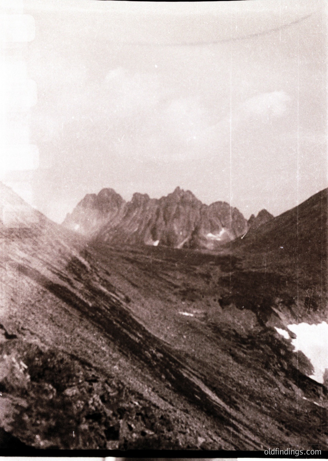 Vintage black-and-white alpine landscape showing jagged peaks and snow patches, likely from mid-20th century. Dramatic lighting highlights rugged terrain and sparse vegetation. Ideal for historical research or vintage travel inspiration.