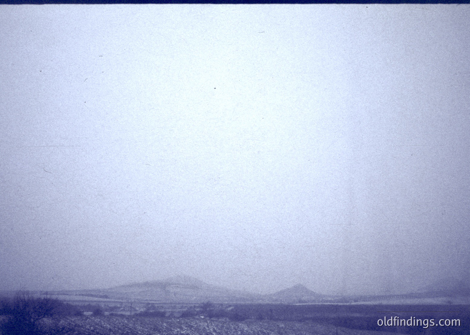 Vintage sepia-toned landscape shot with indistinct, foggy horizon and faintly visible low-lying hills. Likely mid-20th century due to grainy film texture.