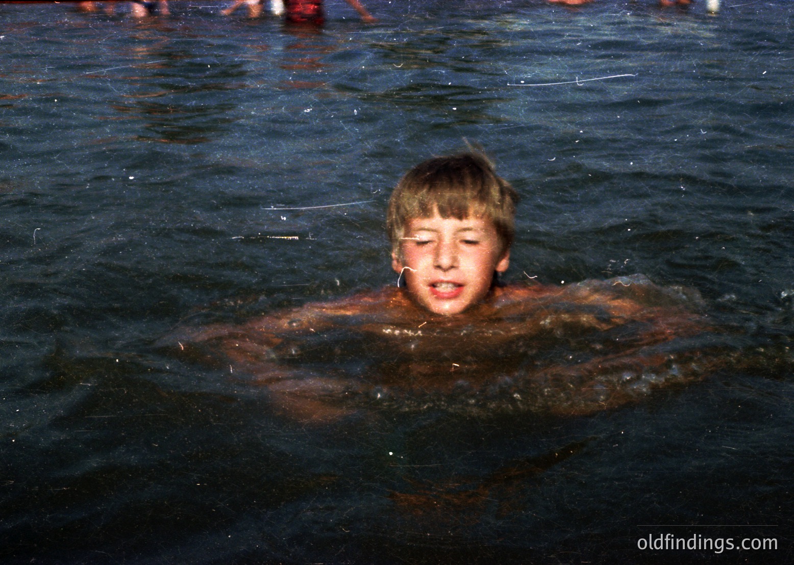Vintage black-and-white photo of a young boy mid-dive in murky water, arms extended forward. The grainy texture and lighting suggest a mid-20th-century snapshot. Ideal for nostalgic or historical research.