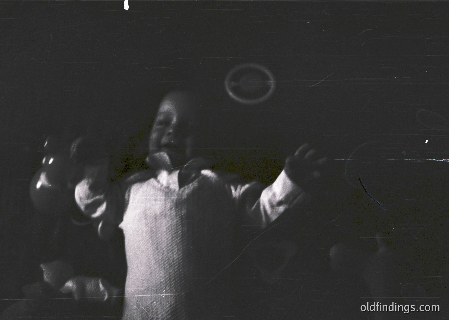Vintage black-and-white photo of a man performing on stage, hands raised in gesture. Lighting emphasizes his silhouette against a dark backdrop, suggesting a live music or theater setting. Possible 1950s–1970s era.