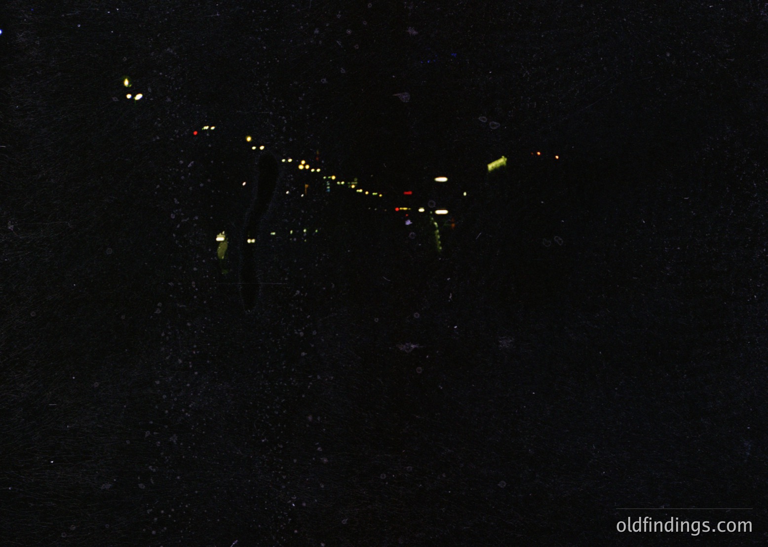 Nighttime aerial view of a sleek, elongated aircraft in flight, illuminated by green and white navigation lights. The design suggests a vintage or military jet, likely from mid-20th century. The starry sky backdrop enhances the dramatic composition.