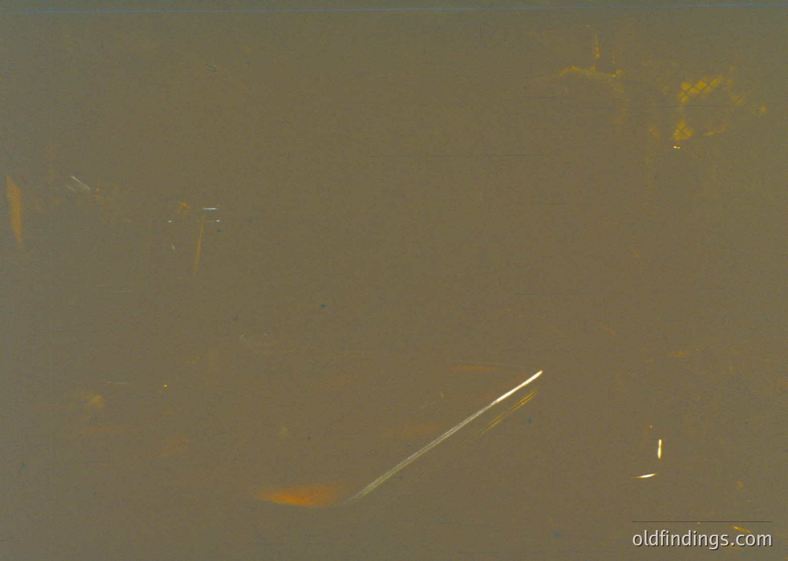 Vintage sepia-toned photograph of a **fishing rod and reel** partially submerged in murky water, likely a lake or river. The blurred background suggests motion or shallow depth. Style resembles early 20th-century photography (). Potential historical context: recreational fishing or documentary imagery.