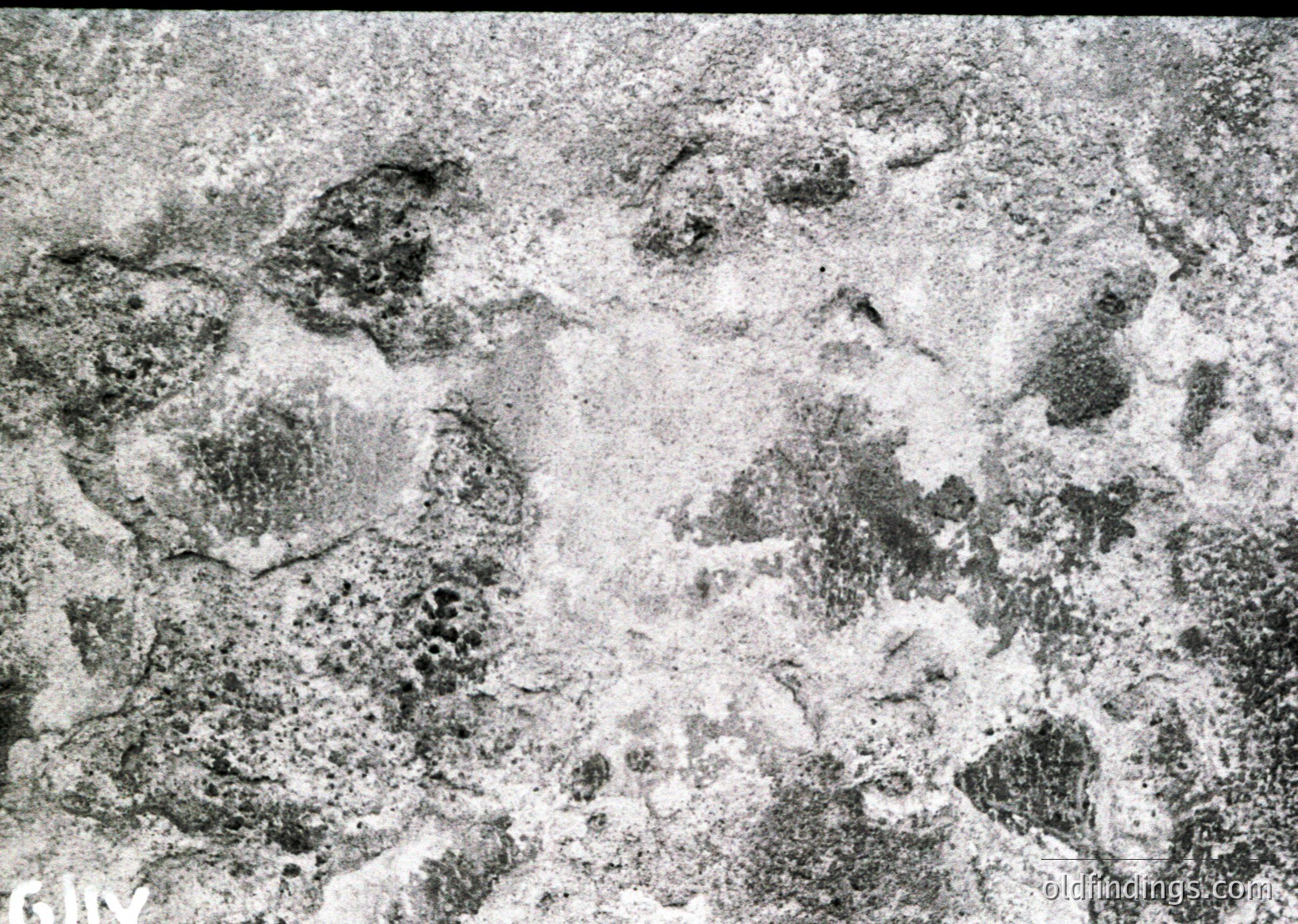 Close-up of heavily eroded, cracked stone surface with granular texture, likely marble or limestone. The weathering suggests prolonged exposure to environmental elements, possibly from a historical or archaeological site.