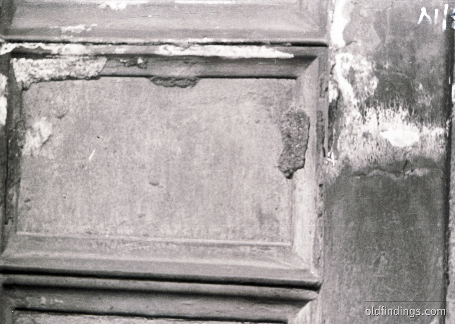 Damaged plaster wall corner with visible cracks and peeling, likely from structural settling or aging. Rectangular panel shows signs of moisture damage and deterioration. Potential historical or older building context.