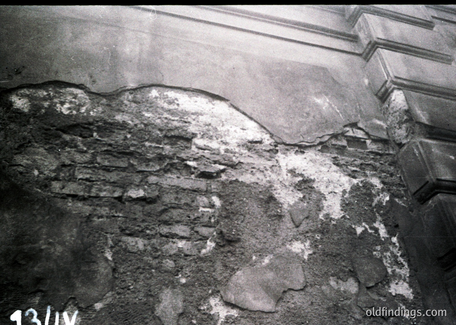 Close-up of deteriorated plaster and exposed brickwork, likely from a historic building’s interior. Cracks and crumbling reveal structural wear, suggesting age or neglect. Possible 20th-century European architecture.