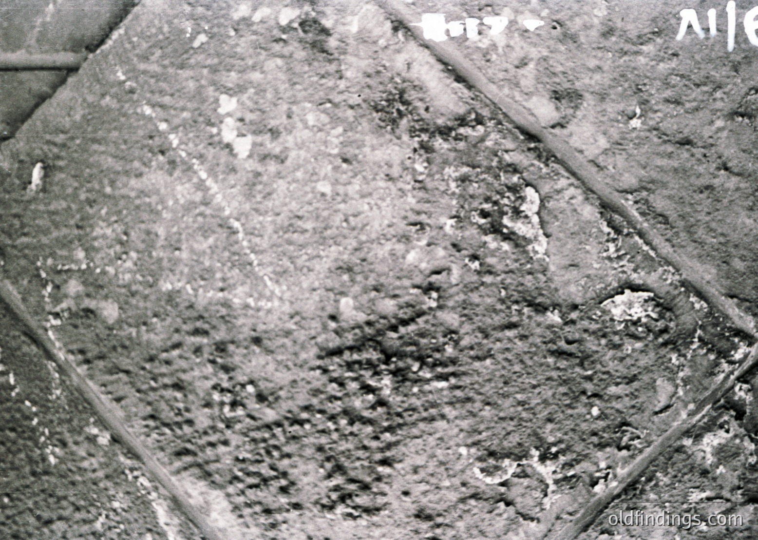 Close-up of weathered concrete surface with visible cracks, erosion, and embedded debris, likely from mid-20th century construction. Textured texture suggests aged infrastructure, possibly from industrial or urban areas.