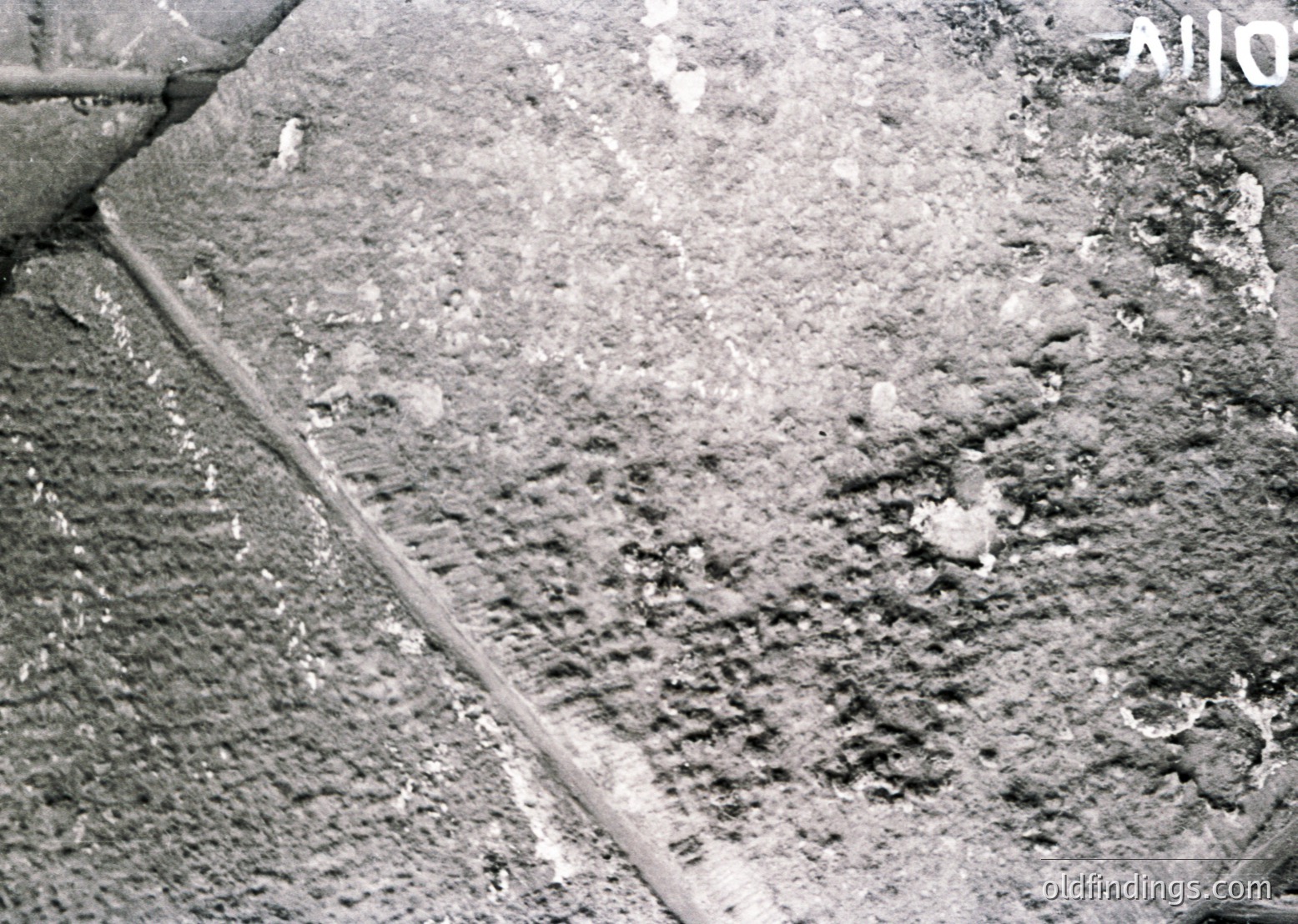 Close-up of weathered concrete surface with visible cracks, erosion, and embedded debris, likely from urban infrastructure. The texture suggests prolonged exposure to elements, possibly industrial or post-construction.
