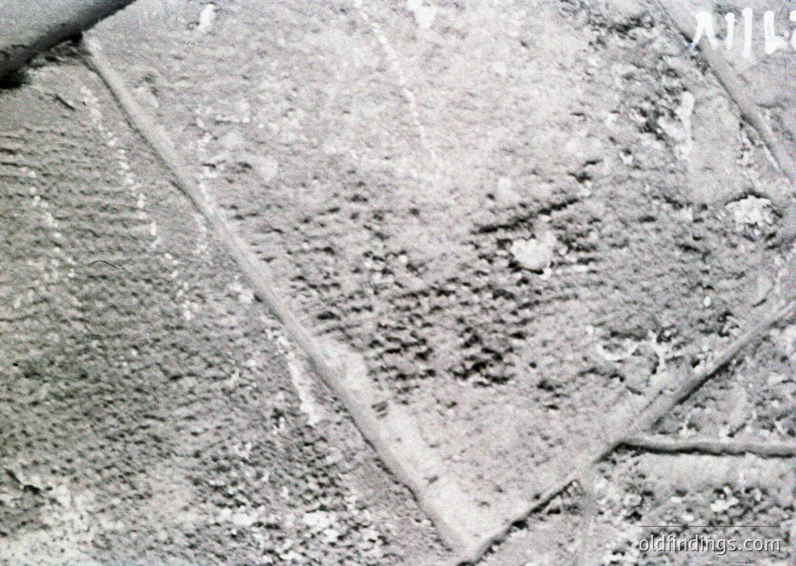 Close-up of weathered concrete surface with visible cracks and erosion, likely from urban infrastructure. The texture suggests long-term exposure to environmental elements.