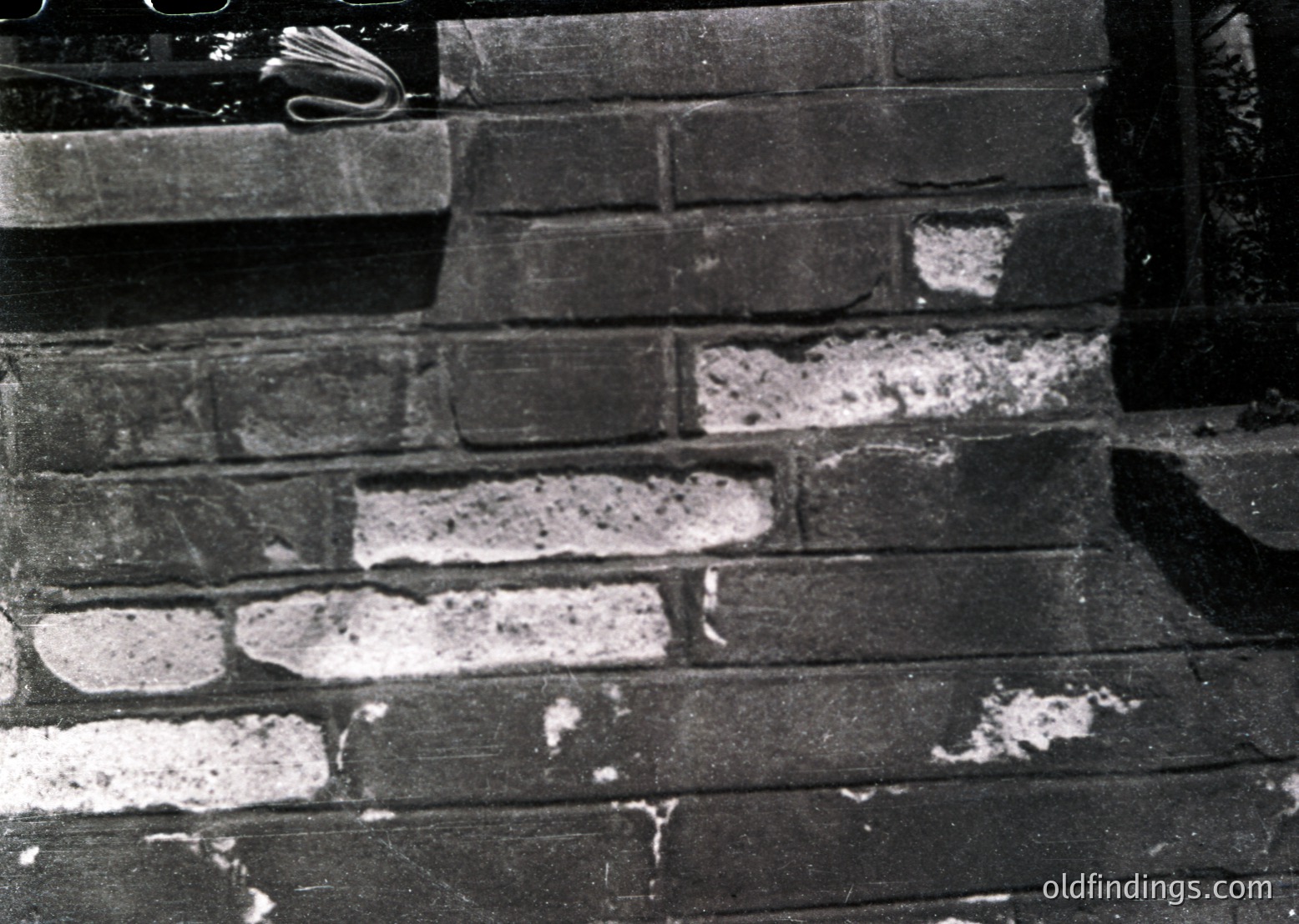 Close-up of weathered brickwork with plaster erosion, revealing mortar lines. Likely mid-20th century industrial or residential facade.