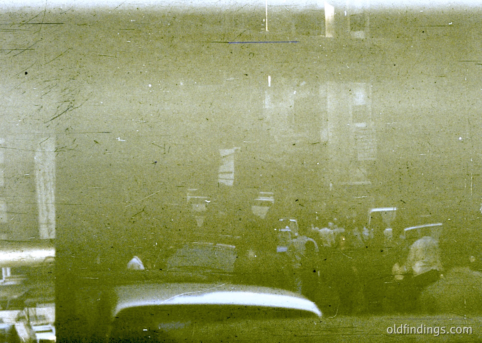 Vintage close-up of a fogged or scratched glass surface reflecting indistinct indoor objects—likely a mirror or window. Reflections show blurred furniture, a light fixture, and a partial view of a door handle. Suggests mid-20th century domestic interior, possibly or .