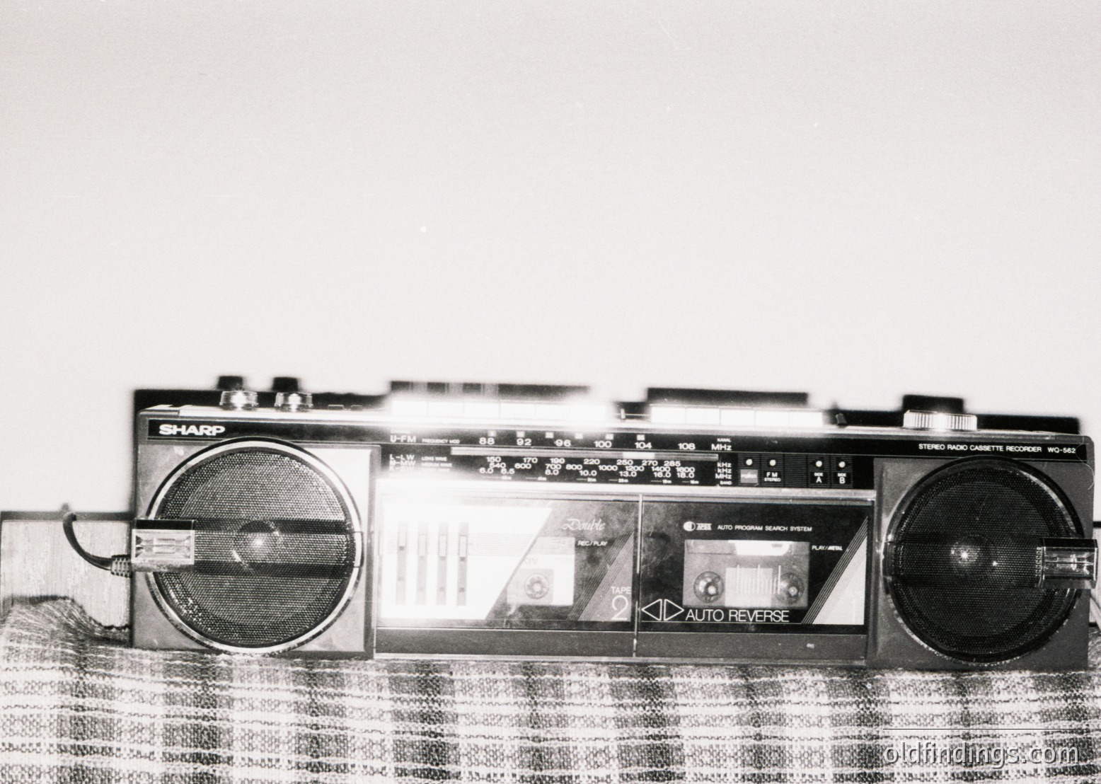 Vintage Sharp EL-562 portable cassette recorder with dual speakers, analog tuning dials, and "Auto Reverse" feature. Mid-20th century design reflects 1970s-1980s consumer electronics. Ideal for retro tech archives, nostalgia content, or historical research on portable audio devices.