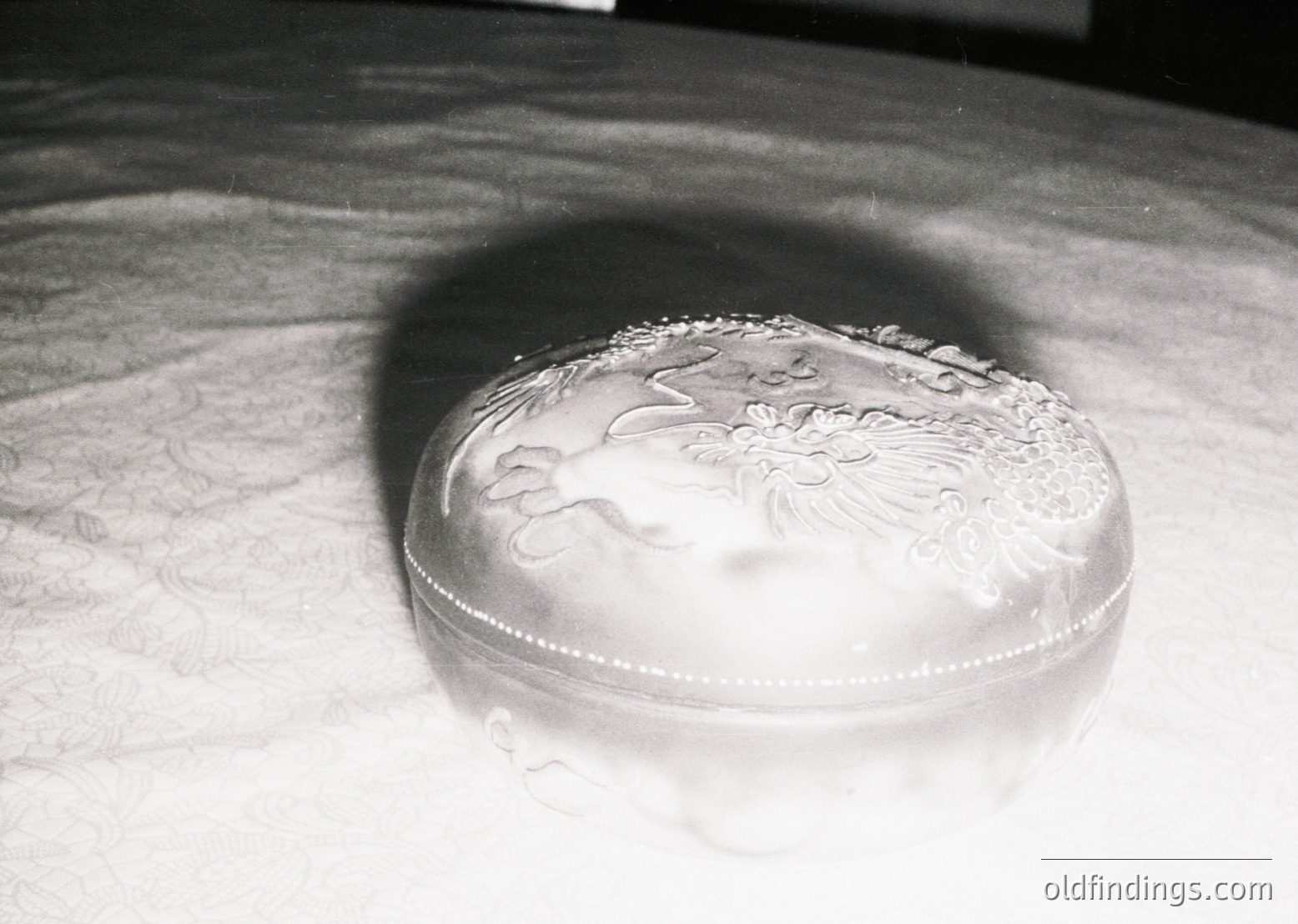 Art deco silver-plated tray with floral and geometric embellishments, cast shadow on textured surface. Likely mid-20th century vintage design.