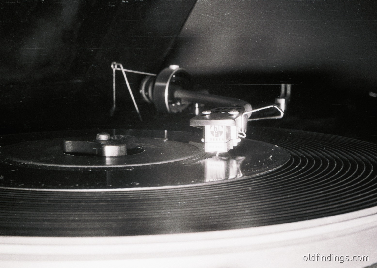 Vintage vinyl record on a turntable with a close-up of the tonearm and stylus in lowered position. The design highlights mid-century audio engineering. Likely 1950s–1970s.